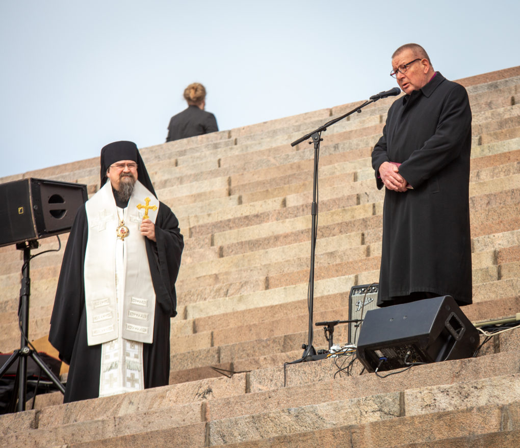 Haminan piispa Sergei kuuntelemassa ja odottamassa puhevuoroaan evankelisluterilaisen kirkon piispa emeritus Eero Huovisen puheen aikana Tuomiokirkon portailla. Kuva: Jouni Nieminen.
